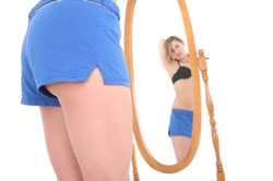 woman looking at her body in the mirror